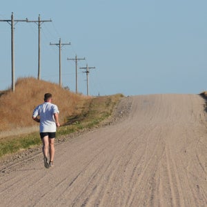 solo runner on dirt road hill