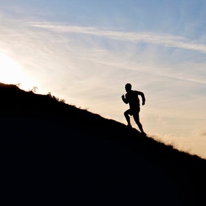 lone runner in silhouette going uphill
