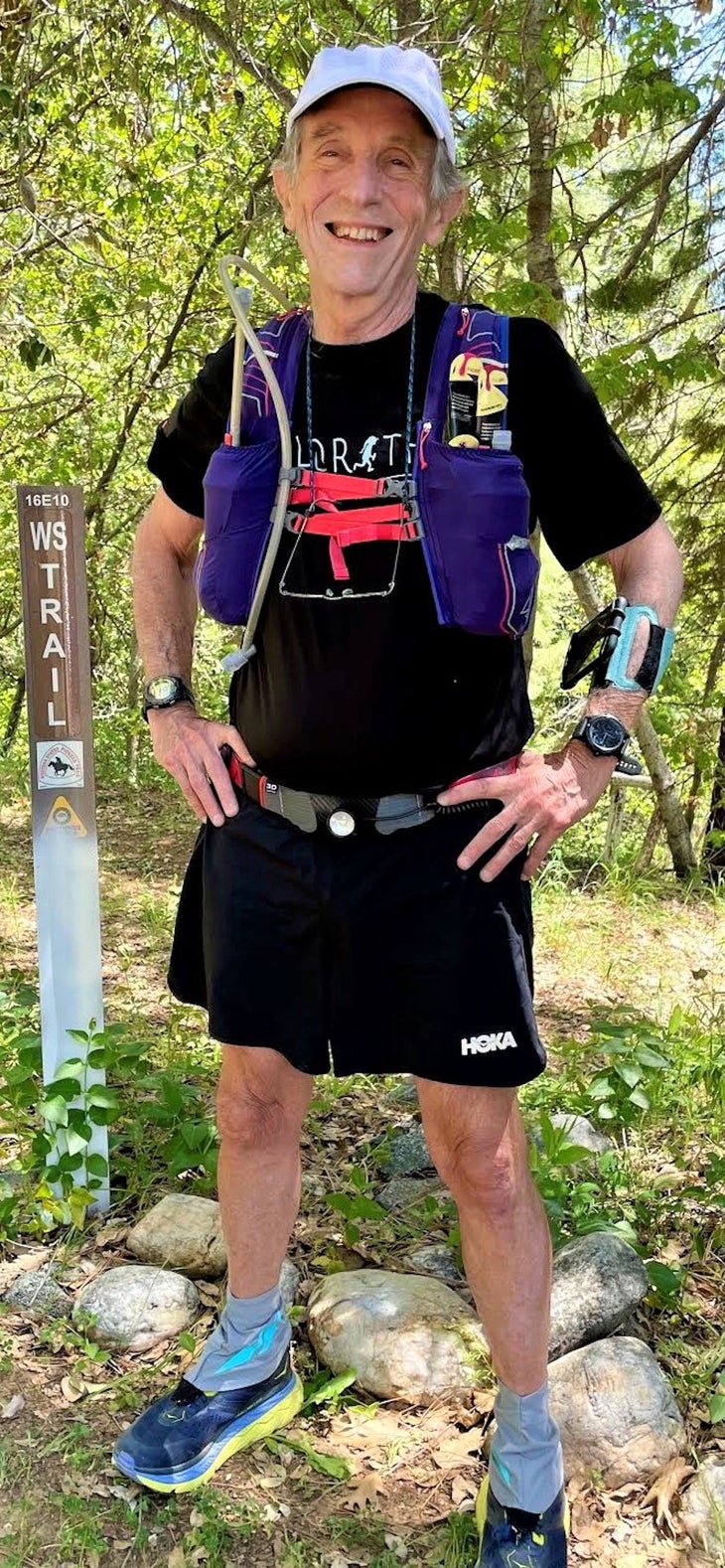 Older looking ultra runner on a trail posing. Full figure shot. 