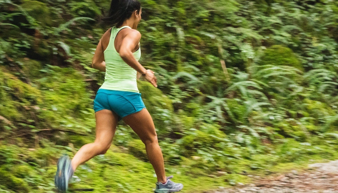Backshot of runner running in lush forest.