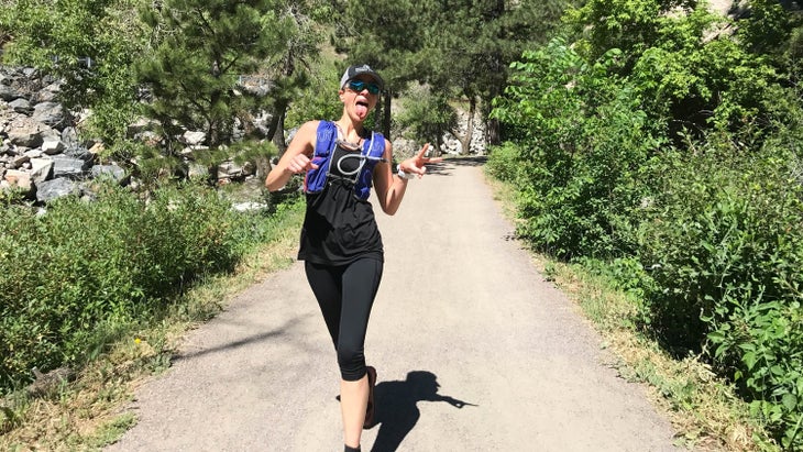 Jill Colangelo running on a trail sticking her tongue out.