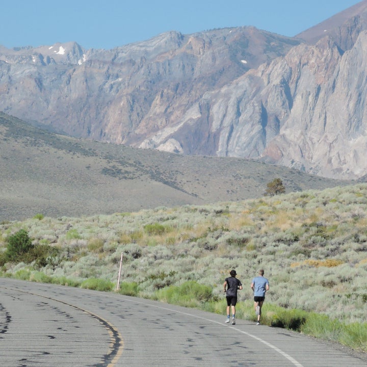 two runners on road in mountains