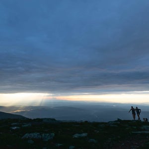 A couple mountain running under an overcast sky
