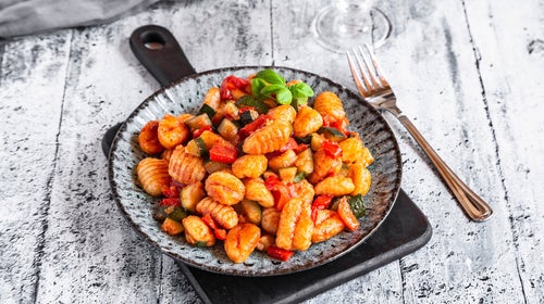 Gnocchi on plate resting on gray wood table