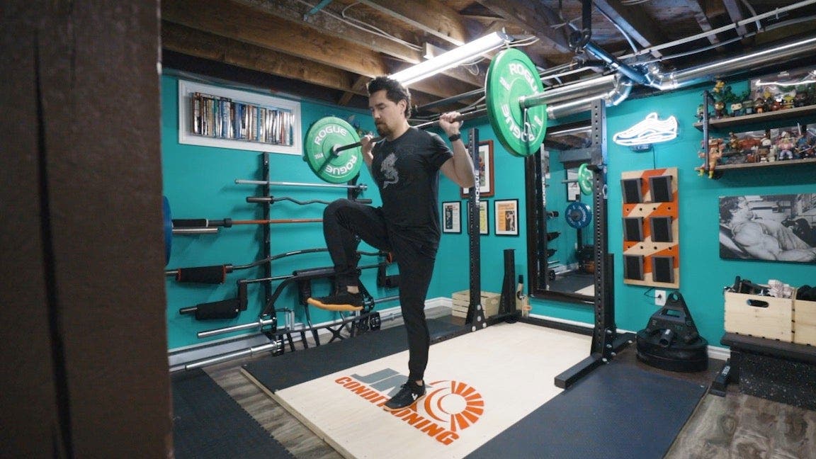 Man with barbell lifting knee up.