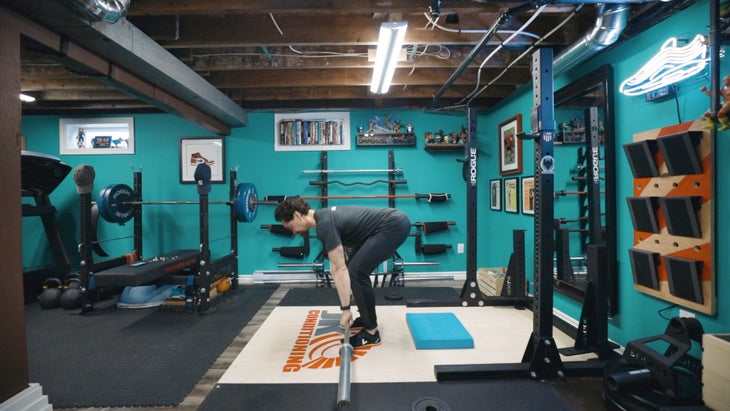 Man bending over about to pick up a barbell.