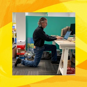 a man kneels while working at his desk