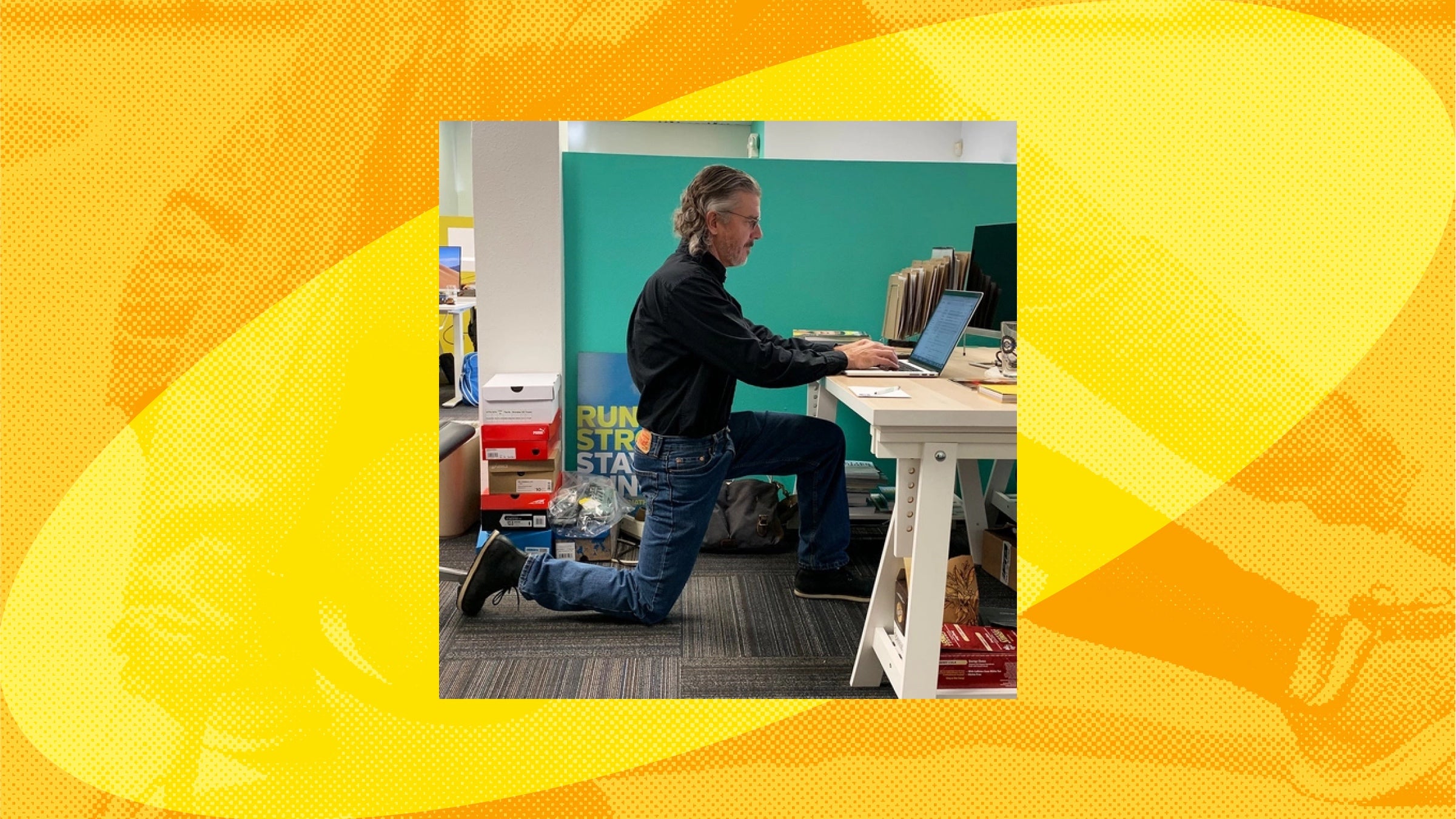 a man kneels while working at his desk