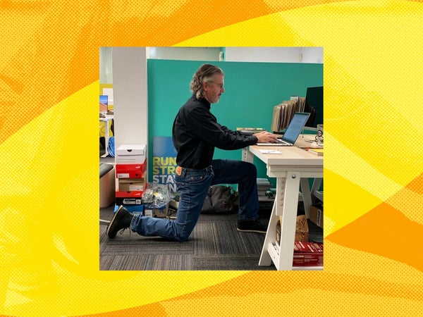 a man kneels while working at his desk