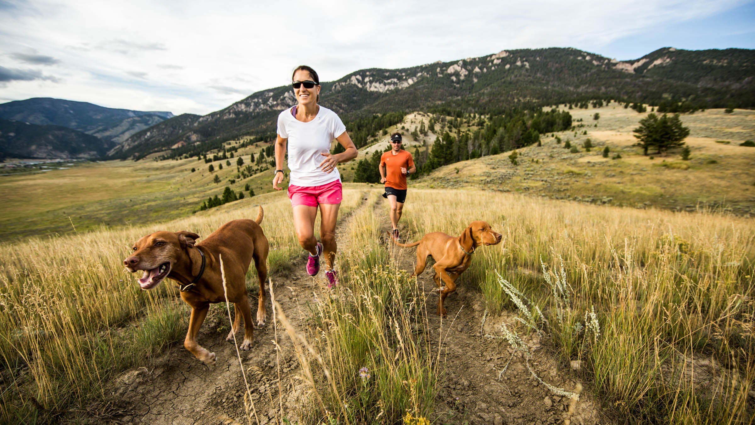 A man and woman trail running with their dogs