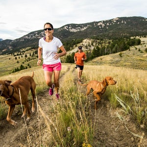 A man and woman trail running with their dogs