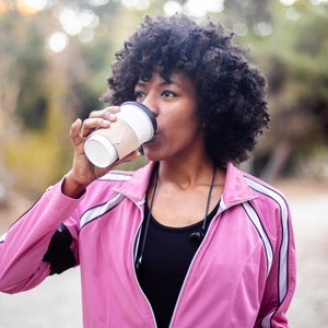 A young black woman walking with a cup of coffee