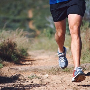 Shot of man's legs while he runs on trail.