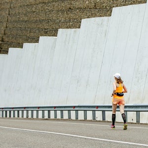woman running alone on a road, downhill