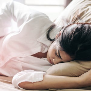 Woman Touching Abdomen While Sleeping On Bed At Home