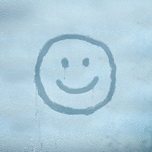 Smiley face drawn over condensated glass