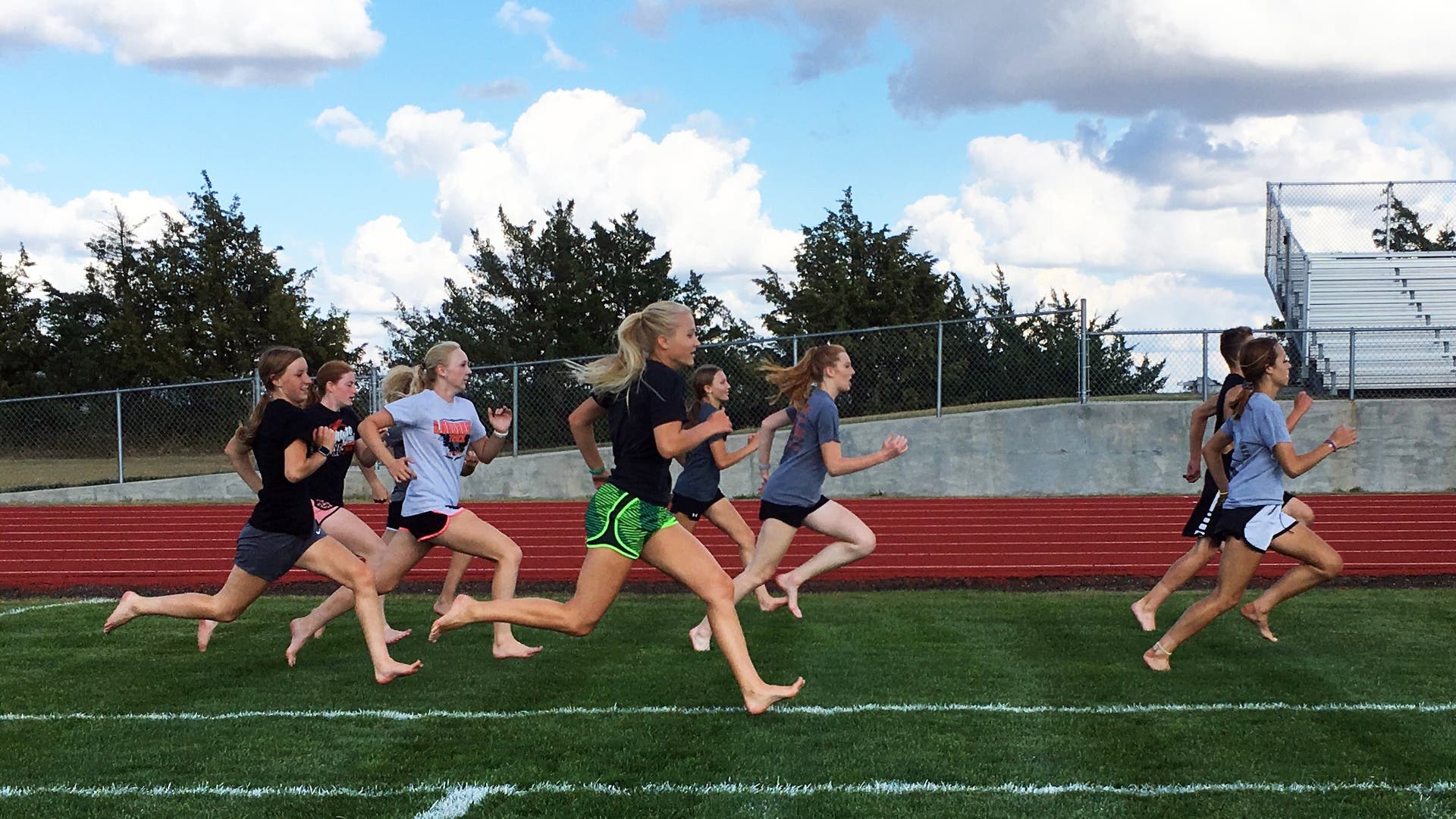 female runners doing barefoot strides on grass