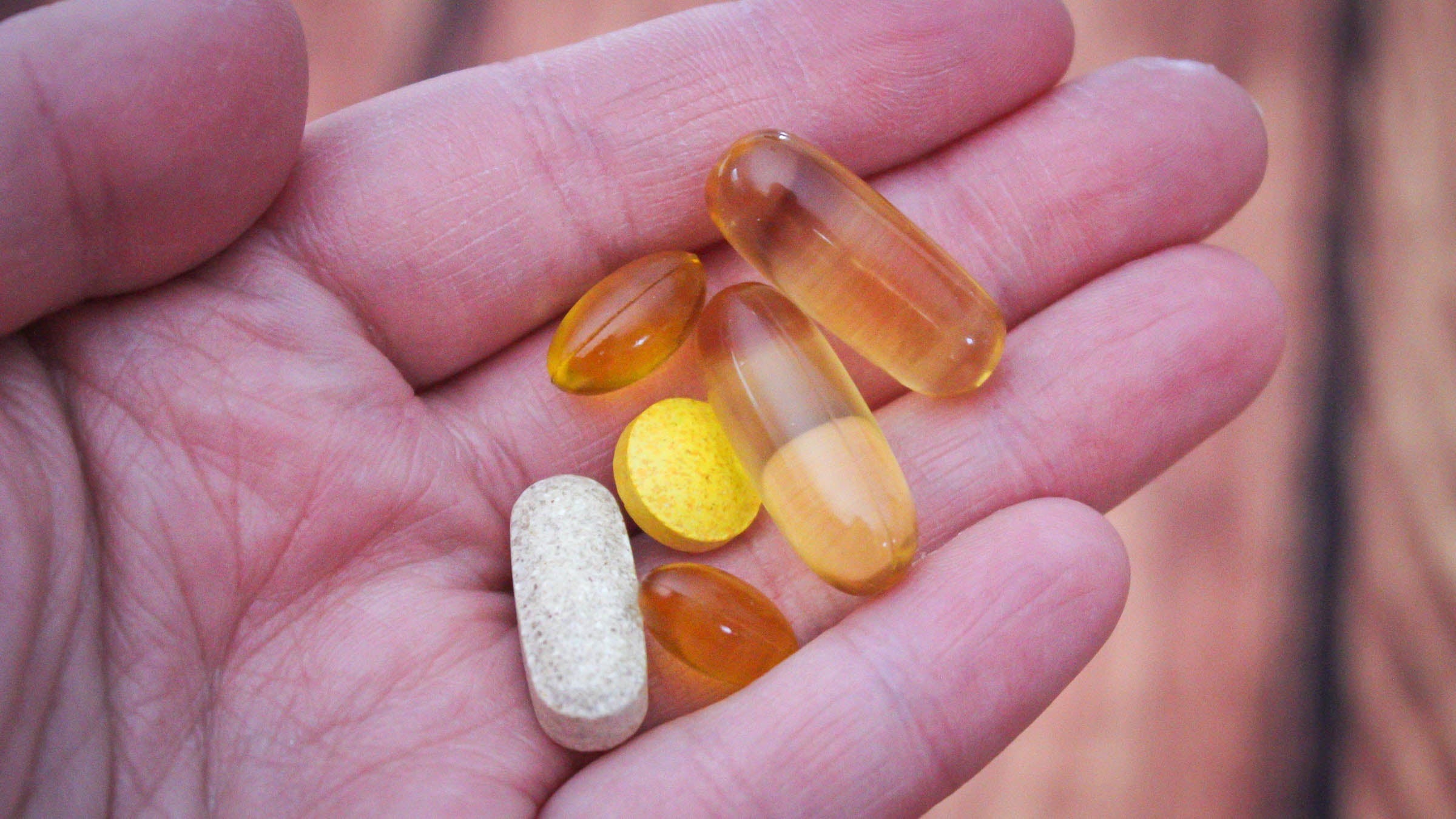 Close up of hand holding a variety of supplements