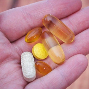 Close up of hand holding a variety of supplements