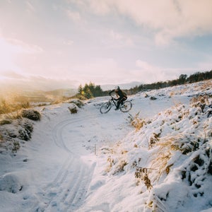 Mountain Biker Riding A Berm On Snow-Covered Trails