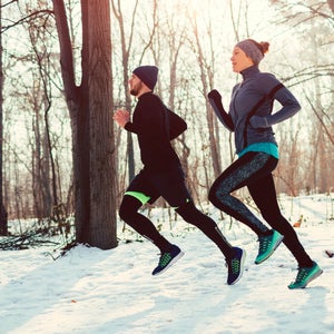 Man and woman jogging during cold winter day in park