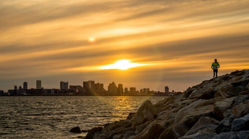 Man runs with Boson skyline behind him at sunset.