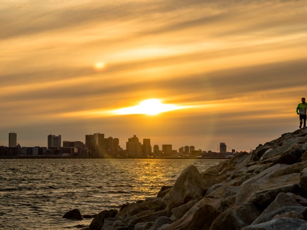 Man runs with Boson skyline behind him at sunset.