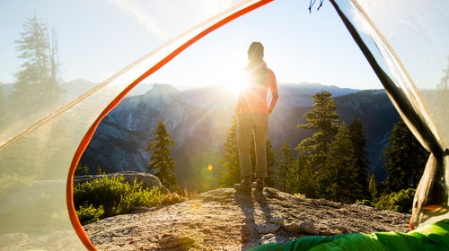 A woman taking in the view of Half Dome at sunrise while camping in the mountains.