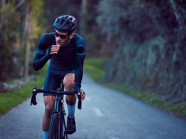 Professional cyclist riding bicycle and eating snack bar outdoors