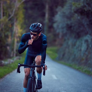 Professional cyclist riding bicycle and eating snack bar outdoors