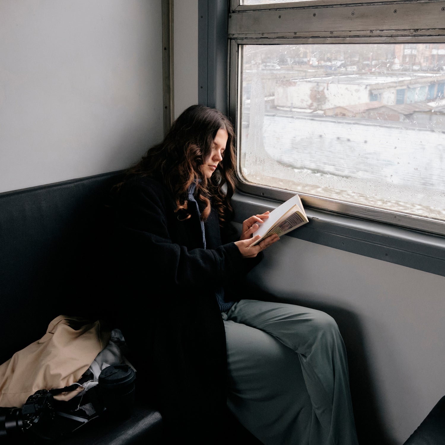 Person reading a book on a train in winter