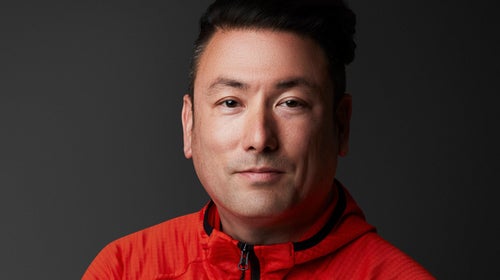 new Mountain Hardwear president Troy Sicotte, wearing red sweater with arms crossed against black backgrounde