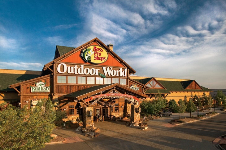 A wide shot of the front of Bass Pro Shops Denver, with a blue sky and evening light.