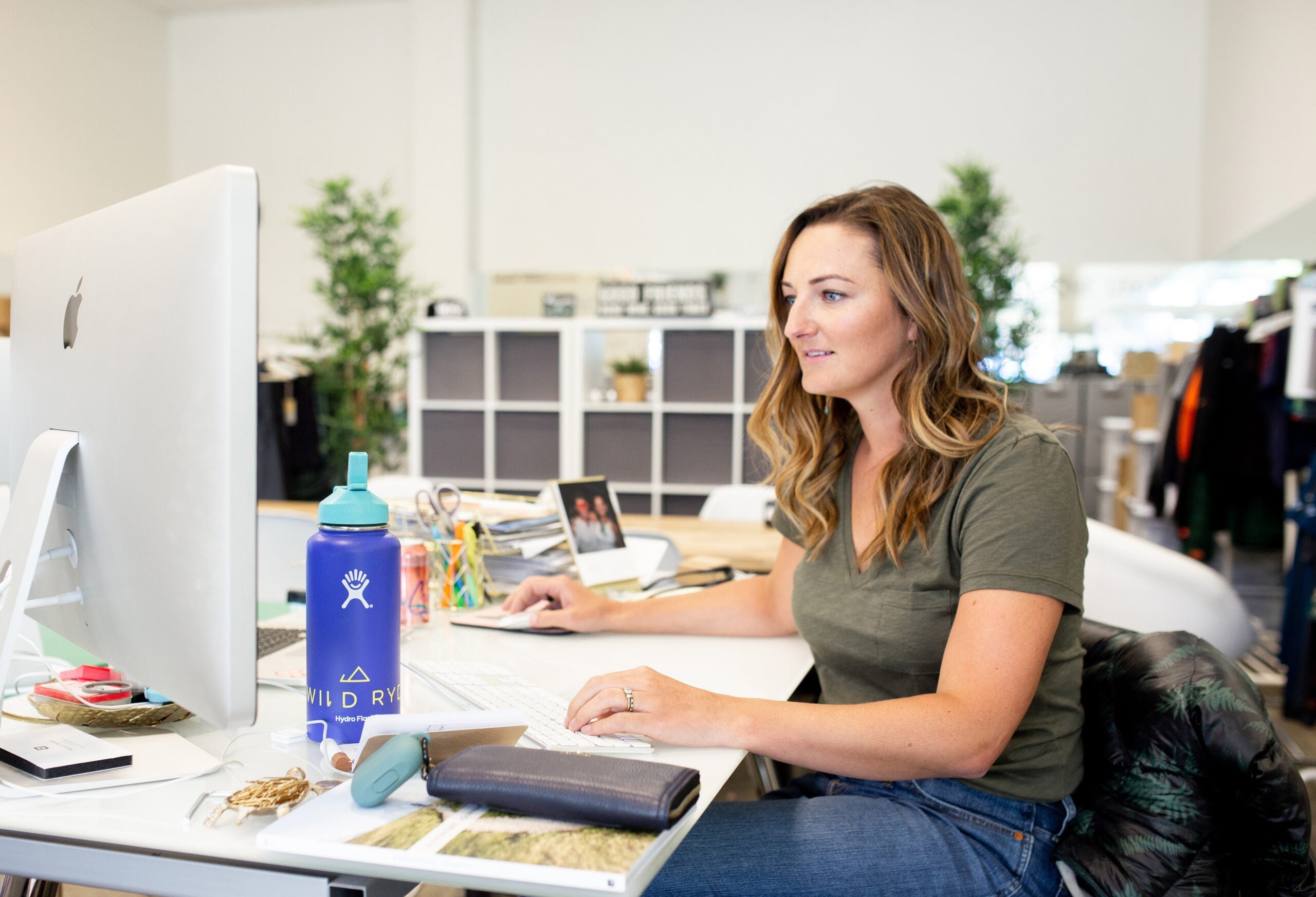 woman with long brown hair sitting at a desk working on a cumpute