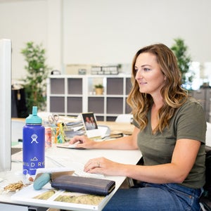 woman with long brown hair sitting at a desk working on a cumpute