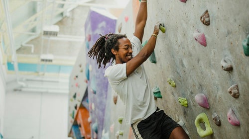 A man rock climbing in a New York City climbing gym.