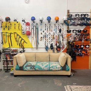 a sales rep showroom with climbing gear hanging on wall an beige couch