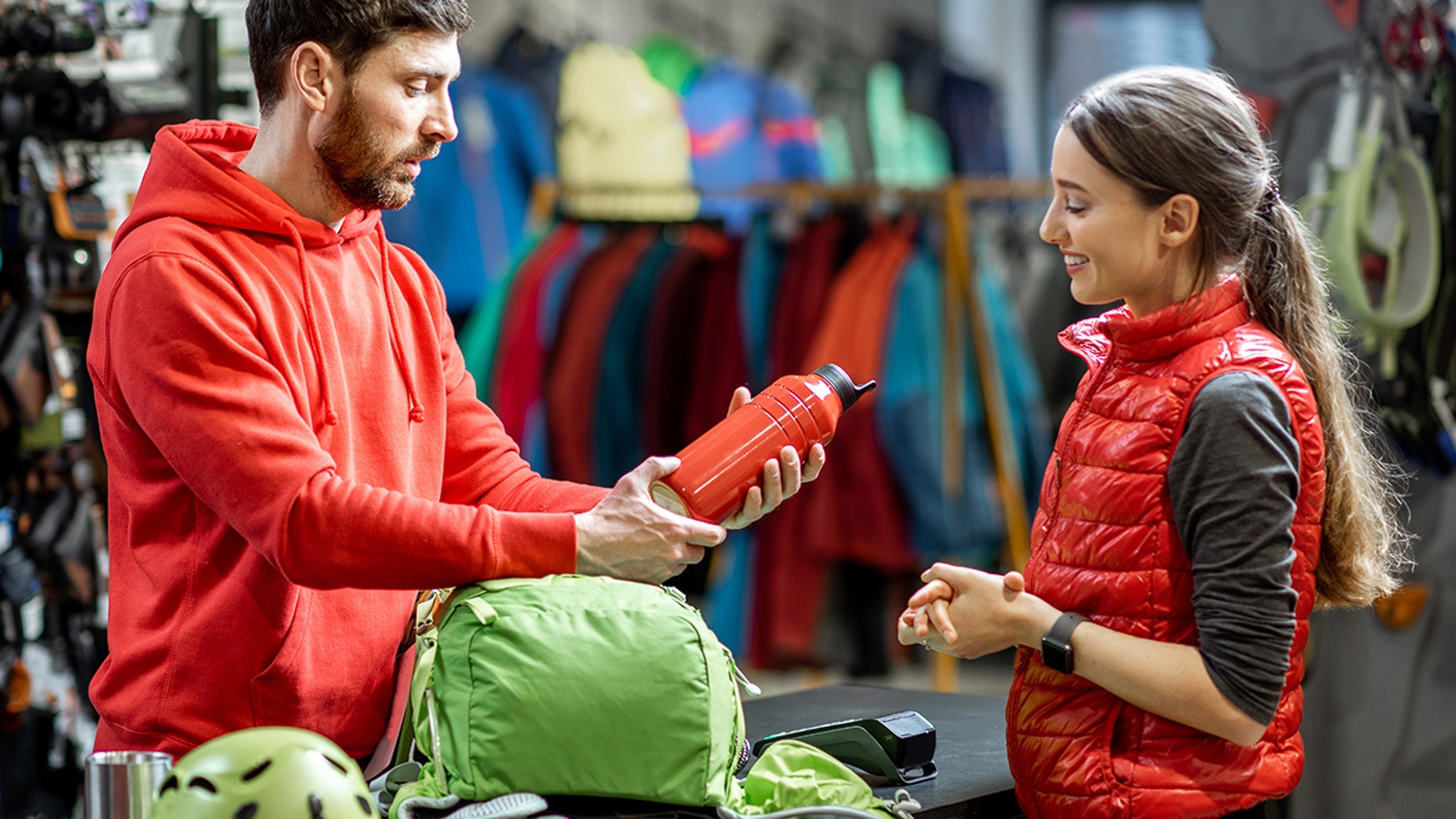 Man at outdoor store shows woman a water bottle