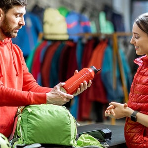 Man at outdoor store shows woman a water bottle