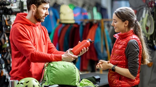 Man at outdoor store shows woman a water bottle