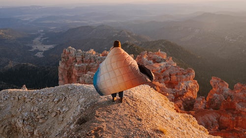 Person wrapped in a quilt, standing above a canyon