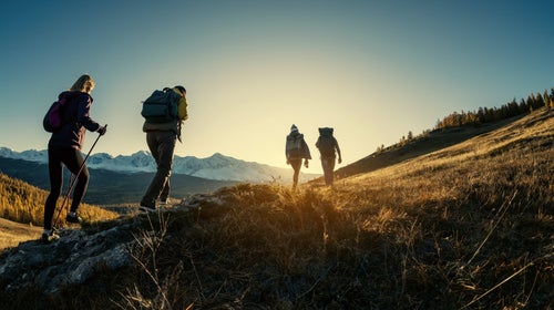 Four people hiking through the hills at sunrise