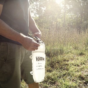 Man standing in a meadow inserting tent poles into a pouch labeled