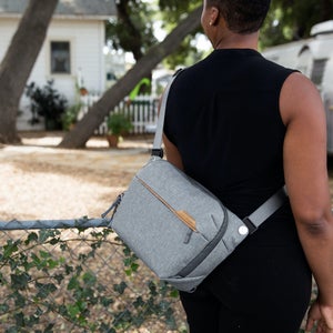 Woman wearing black tank top with gray Peak Designs Everyday Sling bag over her shoulder