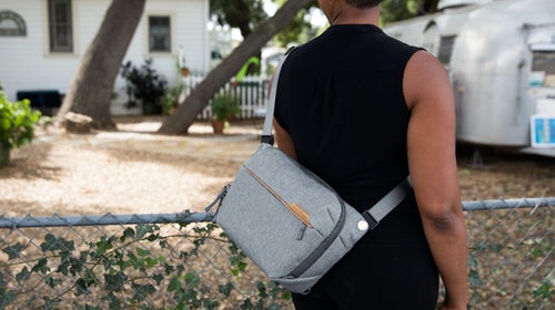 Woman wearing black tank top with gray Peak Designs Everyday Sling bag over her shoulder