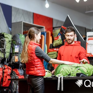 Young woman buying sports goods standing with salesman at a counter