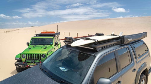 Two jeeps on the beach with roof racks