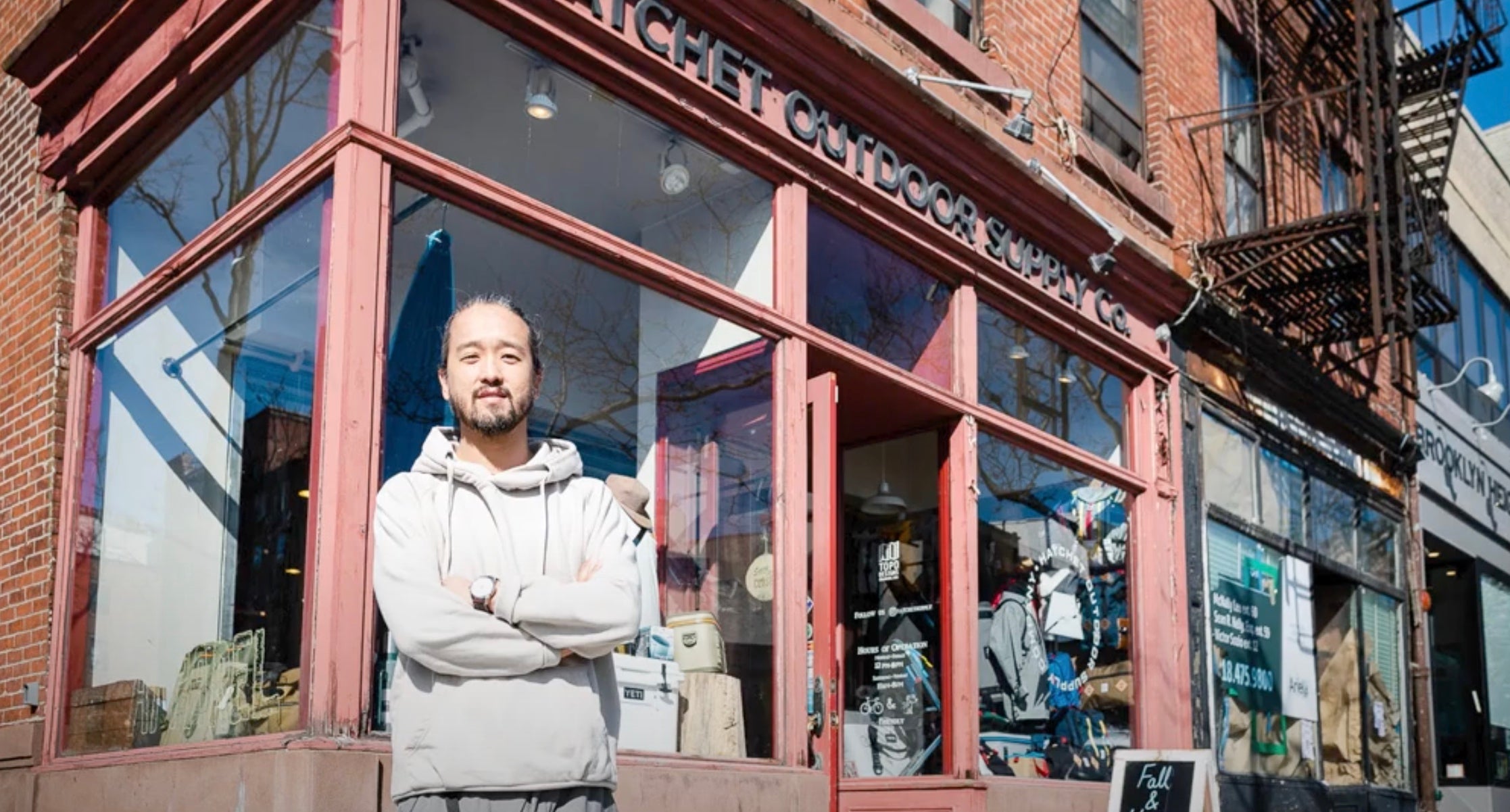 Man standing in front of a store with arms crossed