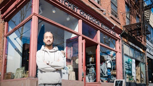Man standing in front of a store with arms crossed