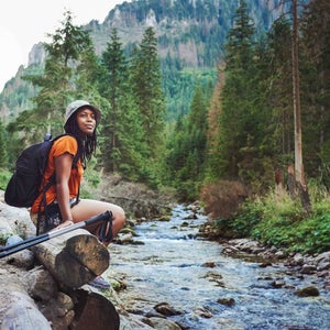 Woman sitting on a rock by a river